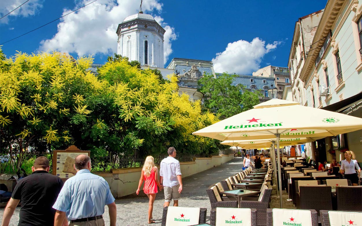 Street view in Bucharest with outdoor café seating and historic architecture.