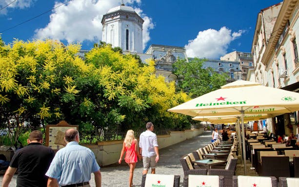 Bucharest street with outdoor café and historic architecture on Communist City tour.