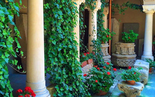 Courtyard with ivy-covered columns and stone carvings in Bucharest, Romania.