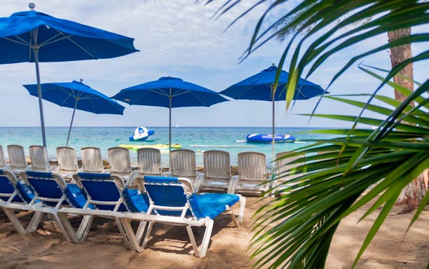 Beach chairs and umbrellas facing the ocean, part of the ATV Mud Kicking and Snorkeling Experience.