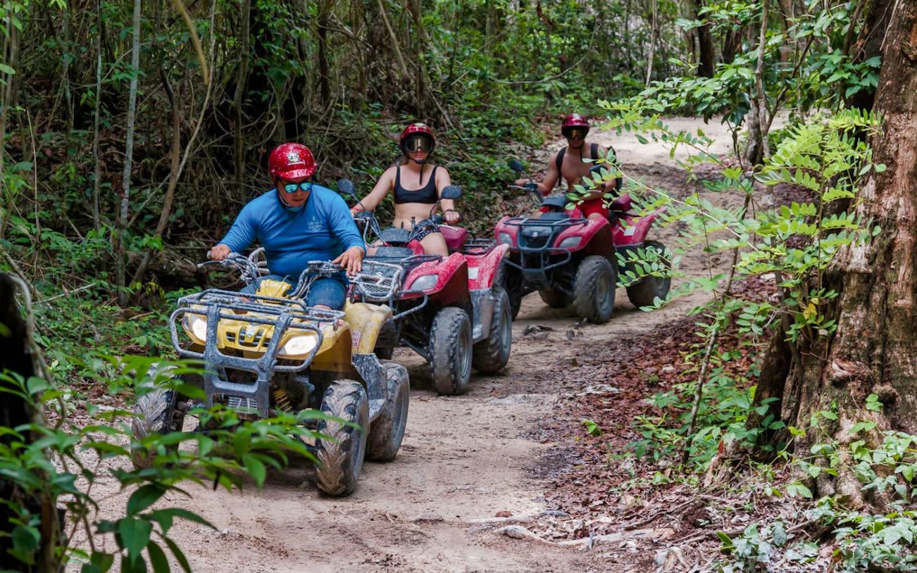 ATV riders navigating a forest trail during a mud kicking and snorkeling tour.