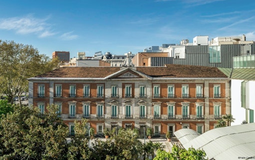 Thyssen-Bornemisza Museum facade in Madrid, Spain, surrounded by trees.