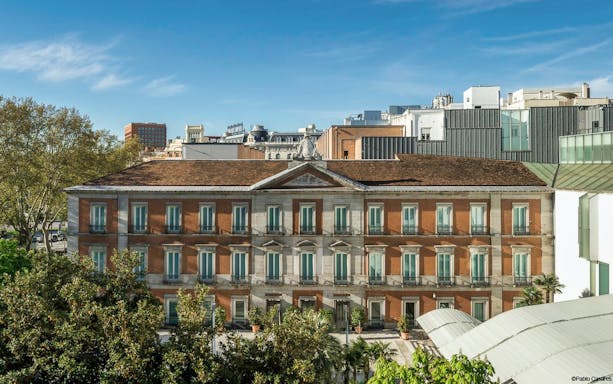 Thyssen-Bornemisza Museum facade in Madrid, Spain, surrounded by trees.