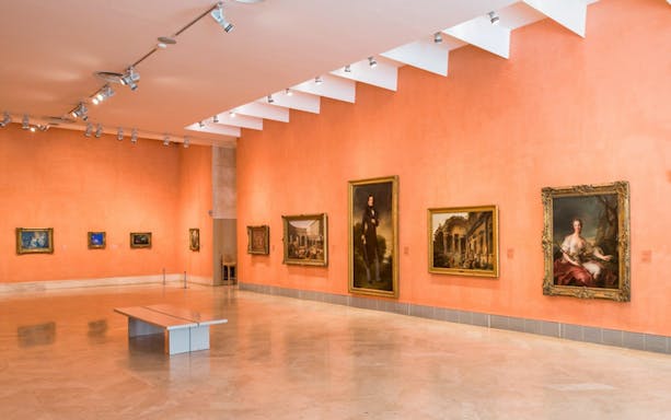 Thyssen-Bornemisza Museum gallery with classic paintings on orange walls, Madrid.