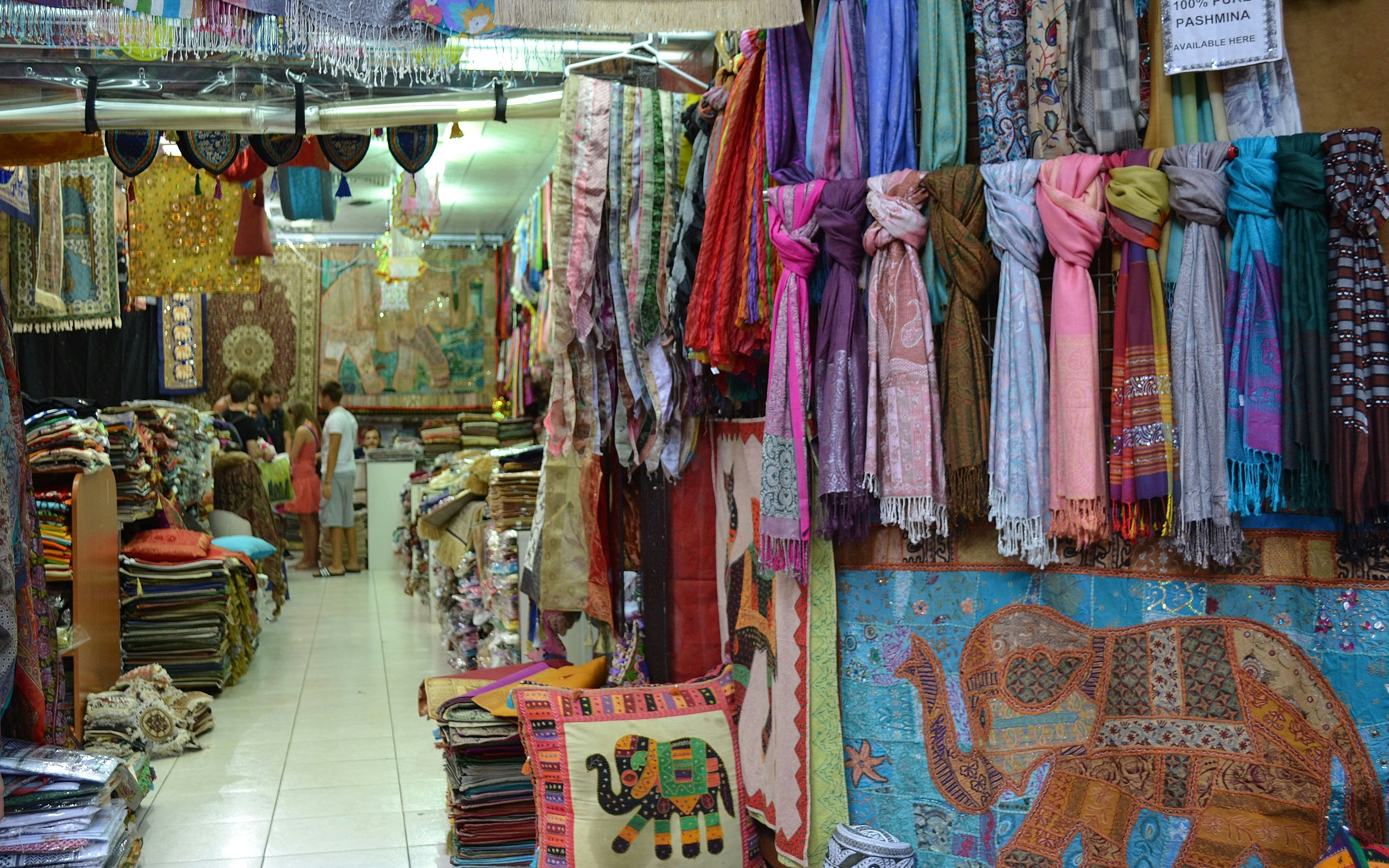 Colorful textiles and scarves displayed in a Dubai souk shop.