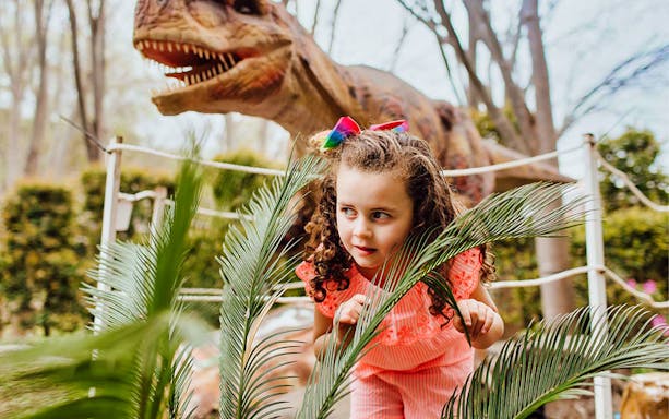 Child exploring near dinosaur model at Mega Creatures Event, Hunter Valley Gardens.