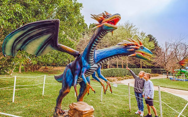 Two children pointing at a large, colorful dragon sculpture at Mega Creatures Event, Hunter Valley Gardens.