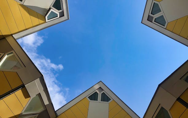 Cube houses in Rotterdam viewed from below against a blue sky.