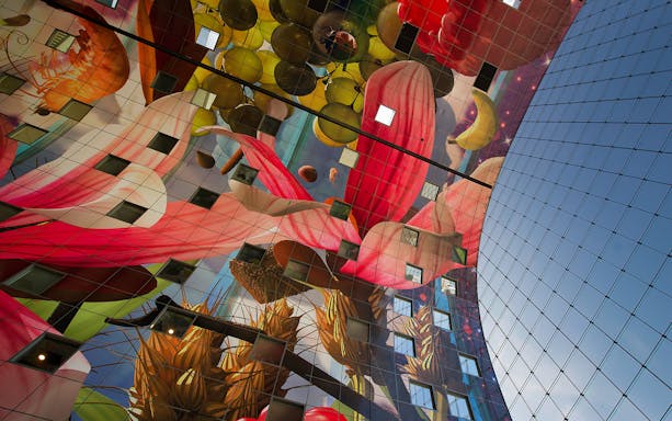 Colorful interior artwork of Markthal ceiling in Rotterdam, featuring fruits and flowers.