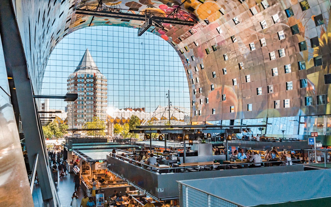 Rotterdam's Markthal interior with market stalls and iconic Cube Houses in the background.