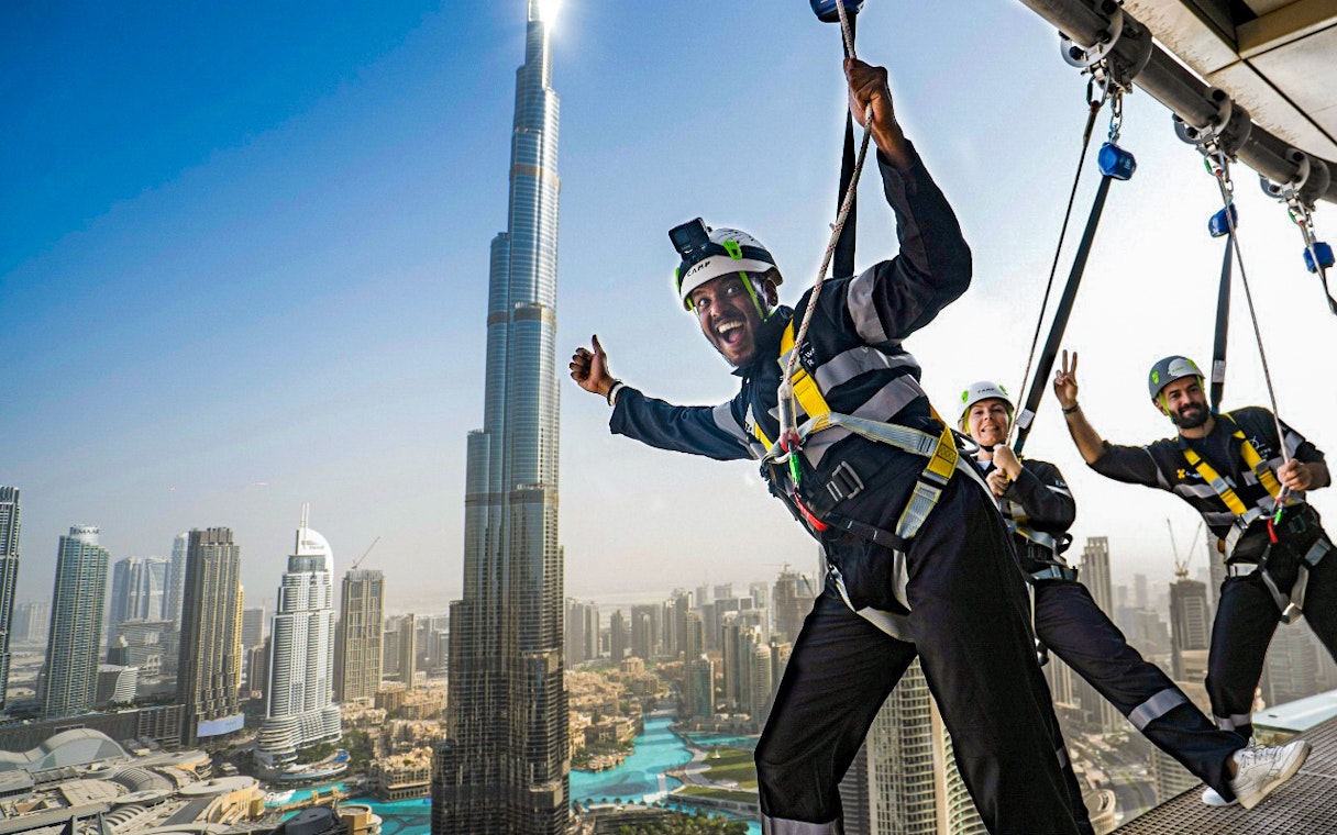 People enjoying a zipline experience with a view of the Burj Khalifa in Dubai.