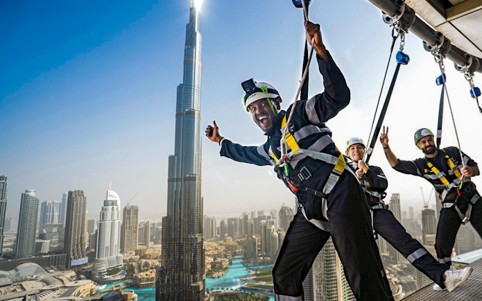 People enjoying a zipline experience with a view of the Burj Khalifa in Dubai.
