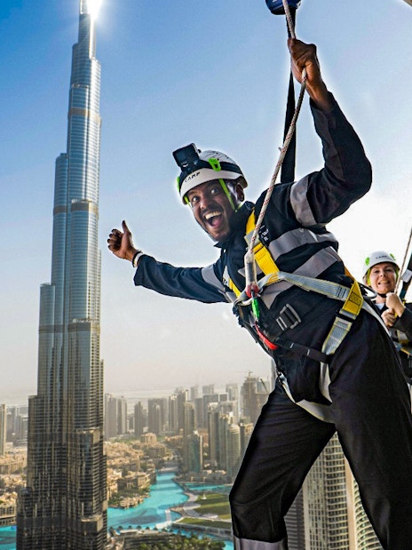 People enjoying a zipline experience with a view of the Burj Khalifa in Dubai.
