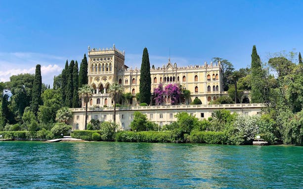 Isola del Garda villa surrounded by lush greenery, viewed from Lake Garda.