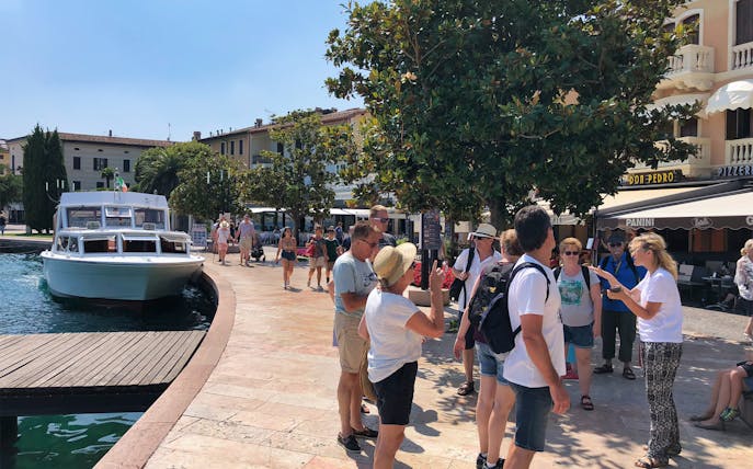 Tourists gather near a boat docked at Lake Garda, Italy, preparing for a cruise to Isola Del Garda.