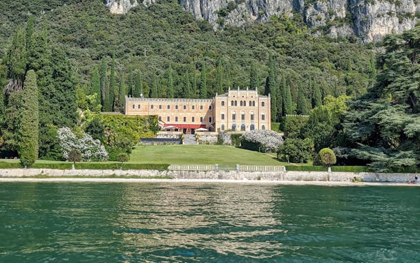 Isola del Garda villa surrounded by lush greenery, viewed from Lake Garda.