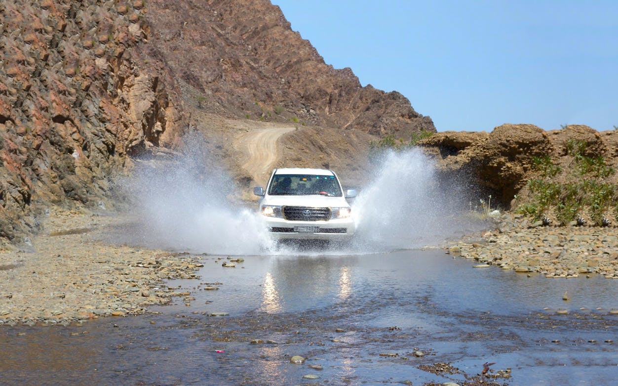 Off-road vehicle crossing a stream during a mountain safari.