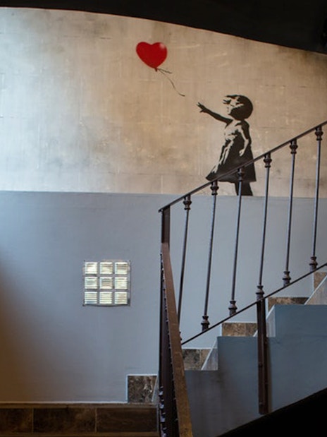 Banksy mural of girl with balloon at Banksy Museum Barcelona staircase.