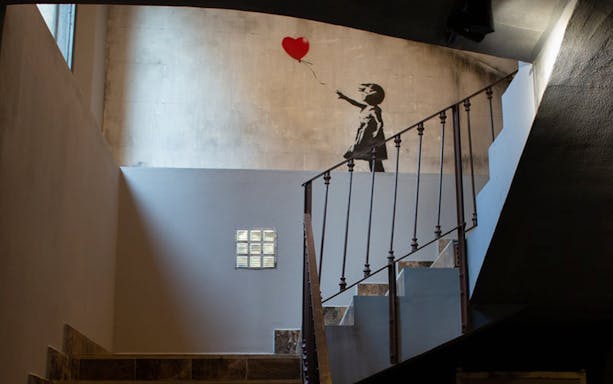 Banksy mural of girl with balloon at Banksy Museum Barcelona staircase.