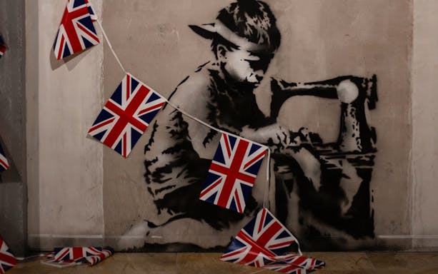 Banksy artwork of a child sewing Union Jack flags, Banksy Museum Barcelona.