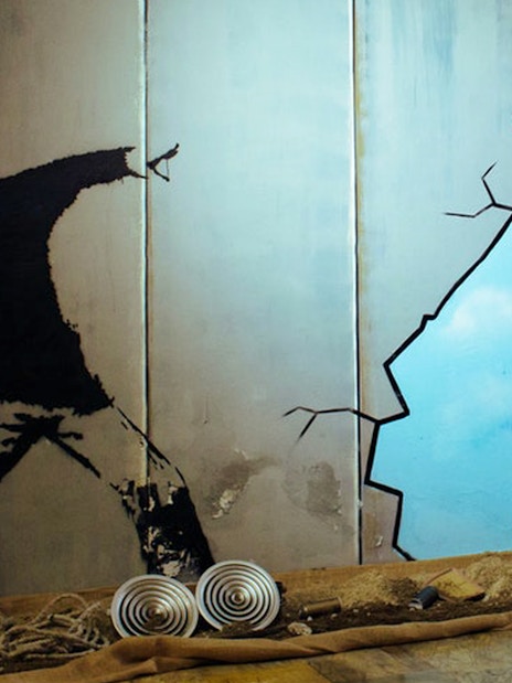 Street art mural at Banksy Museum Barcelona showing a figure throwing flowers.