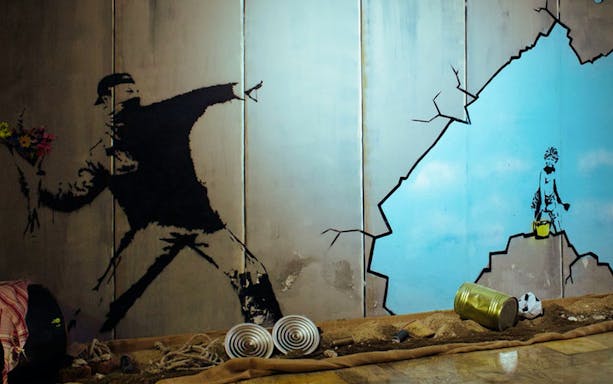 Street art mural at Banksy Museum Barcelona showing a figure throwing flowers.