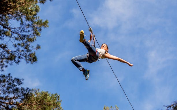 Ziplining adventure at Aventura Amazonia with a person enjoying the ride against a clear sky.