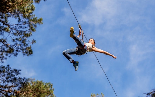 Person ziplining through trees at Aventura Amazonia, Pelayos.