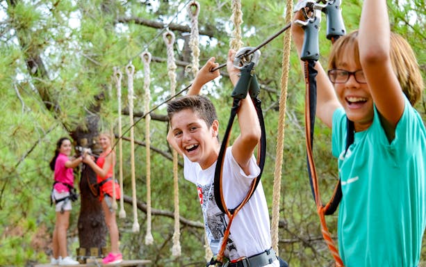 Children enjoying a treetop adventure course at Aventura Amazonia, Pelayos.