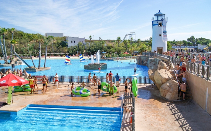 Visitors enjoying the water park at Terra Natura Benidorm with a lighthouse and pool activities.