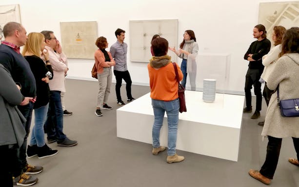 Visitors listening to a guide at Antoni Tàpies Foundation exhibit in Barcelona.