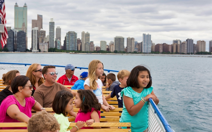 Tourists enjoying a boat ride with the Chicago skyline in the background.