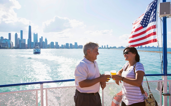 Couple enjoying drinks on a boat with Chicago skyline in the background.