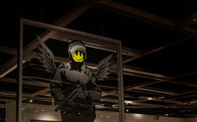 Banksy artwork with smiley face and wings at London exhibition.
