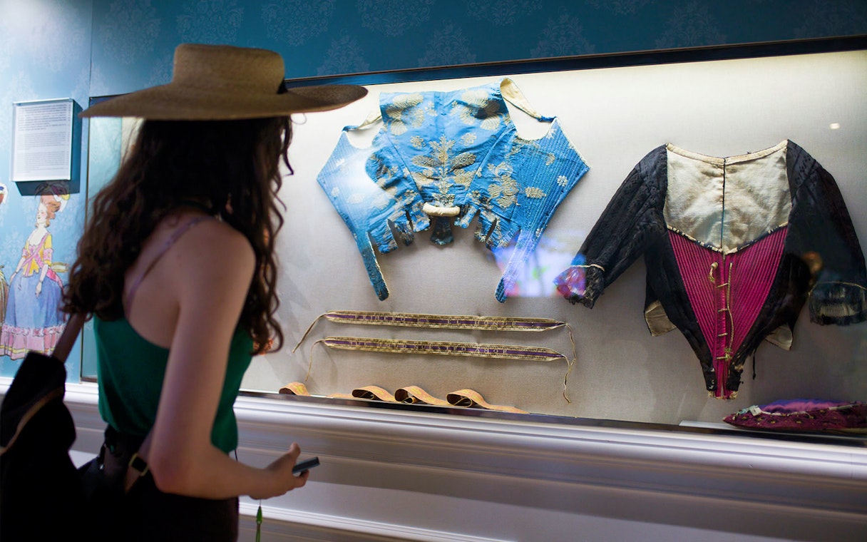 Visitor viewing historical garments at Valencia's Silk Museum.