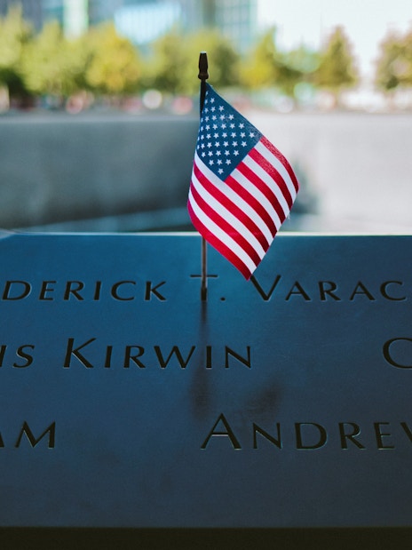 Names engraved at 9/11 Memorial with small American flag, New York City.