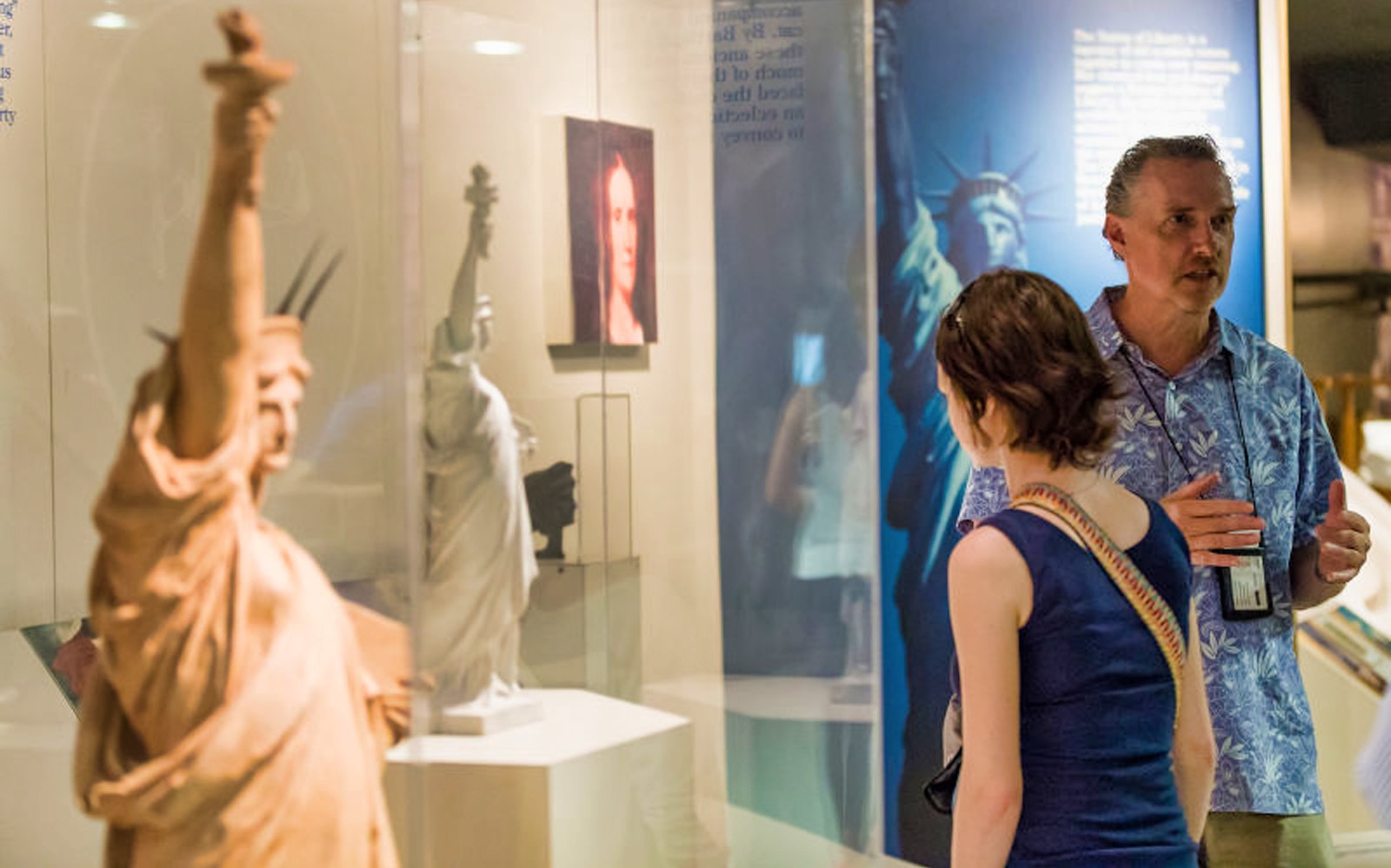 Visitors viewing Statue of Liberty exhibit during guided tour at Ellis Island Museum.