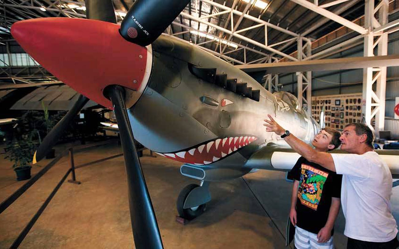 Visitors examining a fighter plane at Darwin Aviation Museum.