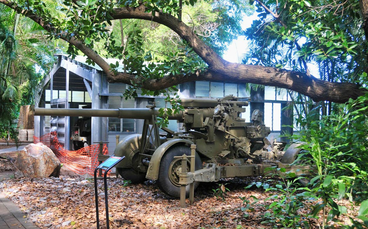 Artillery display at Darwin Military Museum surrounded by tropical foliage.