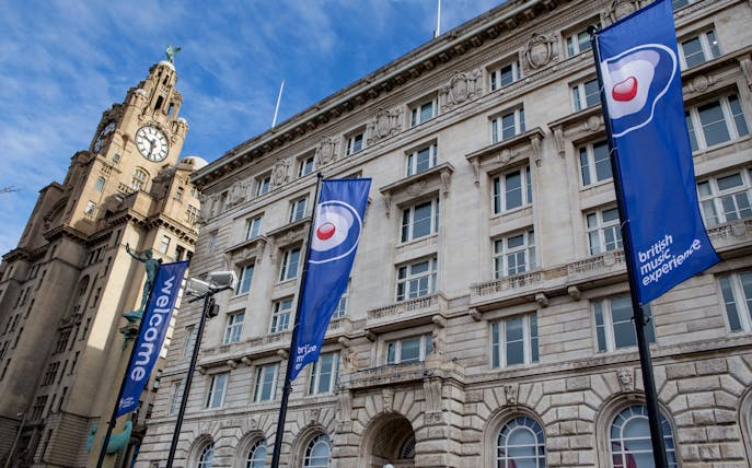 British Music Experience flags outside historic building in Liverpool.