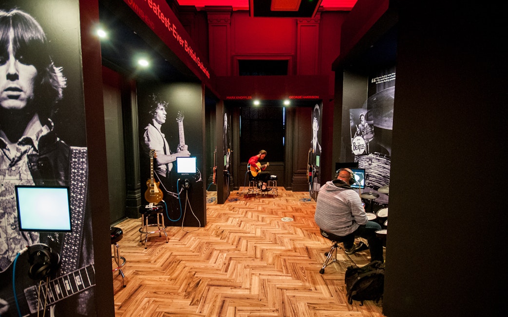 Interactive music exhibit at the British Music Experience with guitars and drum kits.