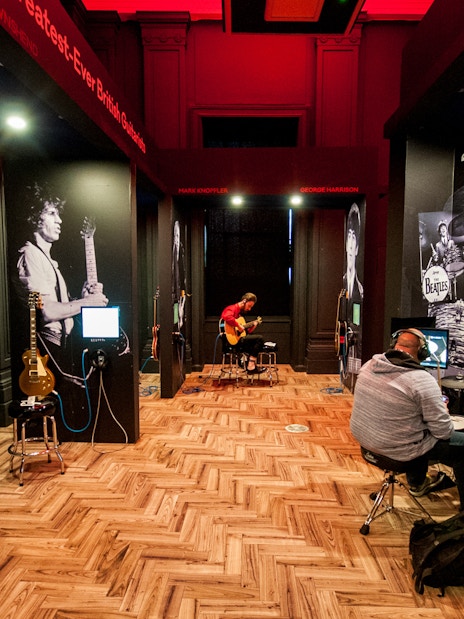 Interactive music exhibit at the British Music Experience with guitars and drum kits.