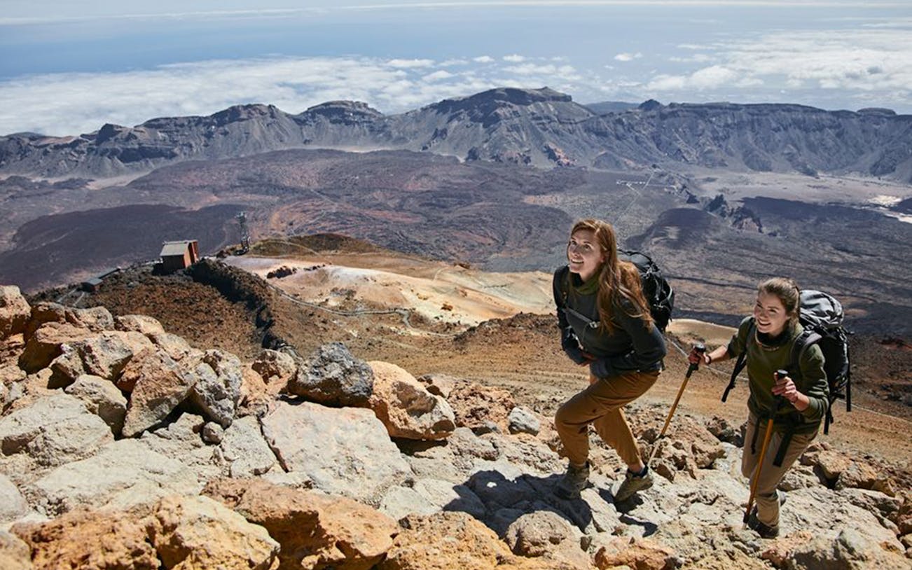 Hikers ascending Teide Crater with cable car station in the background, Tenerife.