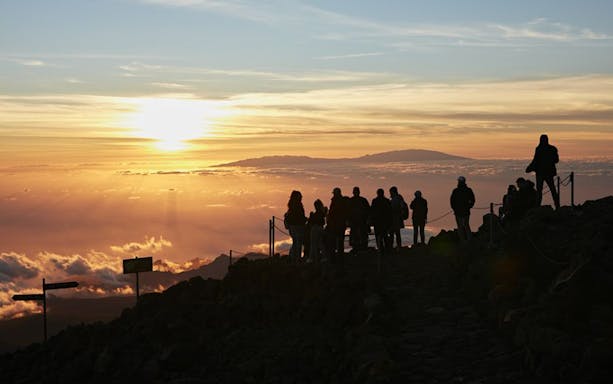 Group observing sunset at Mount Teide, Tenerife, with clouds and distant mountains.