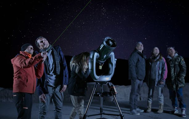Group stargazing with telescope on Mount Teide under a starry sky.