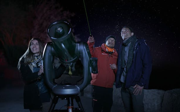 Group observing stars with telescope on Mount Teide tour at night.