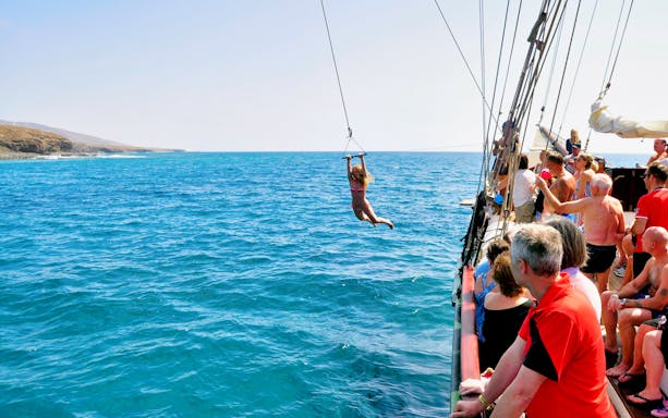 Pirate ship tour in Fuerteventura with a person swinging over the ocean.