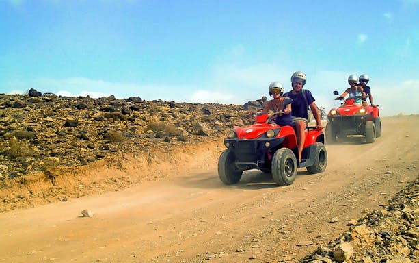 ATV riders on a dirt trail in Fuerteventura, showcasing the island's rugged landscape.