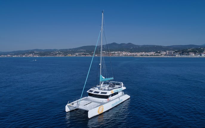 Catamaran sailing near Malaga coastline on a clear day.