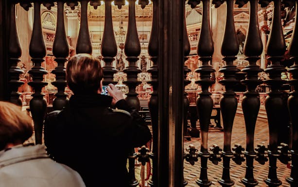 Visitor photographing ornate interior through iron gate in Naples Old Town Centre.